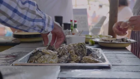 Chef preparing oysters for customers at a bar while others are eating and Stock Footage