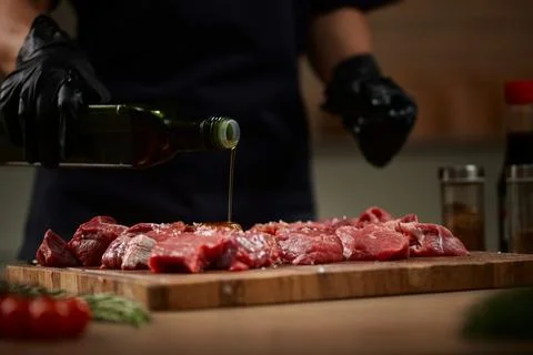Chef preparing raw beef meat with olive oil and salt Stock Photos