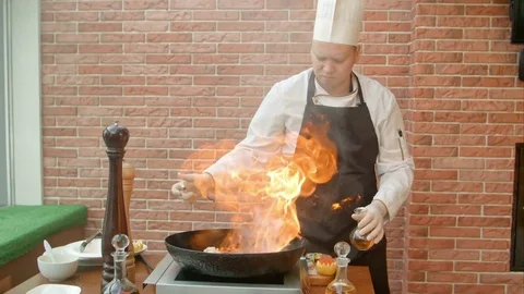 Chef preparing seafood in pan with alcohol in big flame Stock Footage 74934219