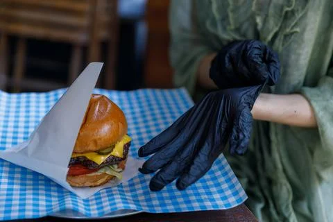 A Chef Preparing to Serve a Delicious Cheeseburger While Wearing Black Gloves on Stock Photos