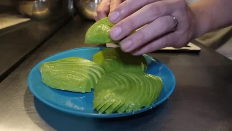 Chef Preparing Sliced Avocado Halves on Plate in Commercial Kitchen Video stock 347689518