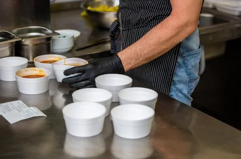 Chef preparing soup to a box in the restaurant for food delivery service to home 库存照片