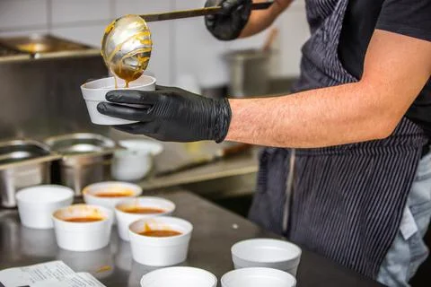 Chef preparing soup to a box in the restaurant for food delivery service to home Stock Photos