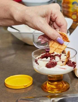 Chef preparing special dessert with fresh cream, cherry, cookies and nuts i.. Stock Photos