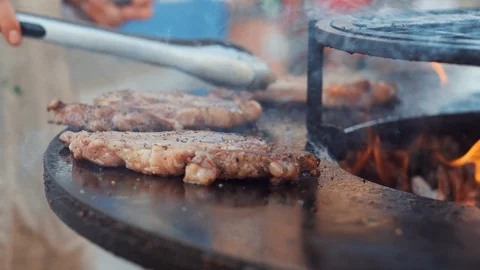 Chef is preparing steak on grill, turning pieces by tweezers Stock Footage 115672550