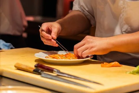 Chef preparing sushi with precision using chopsticks in a vibrant kitchen Stock Photos