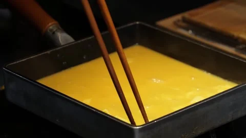 Chef Preparing Traditional Japanese Rolled Omelette (Tamagoyaki) in Square Pan Stock Footage 333527307