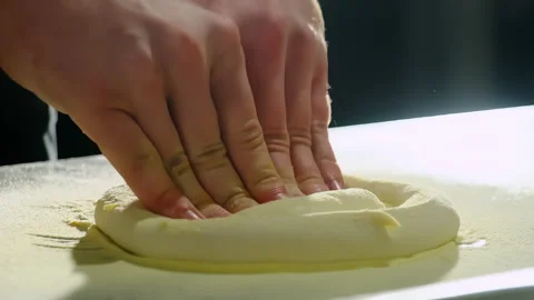 Chef presses dough center on floured board shaping thick rim Stock Footage 325069451