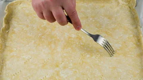 A chef pricks the raw cottage cheese dough with a fork on parchment paper. Stock Footage 341552371