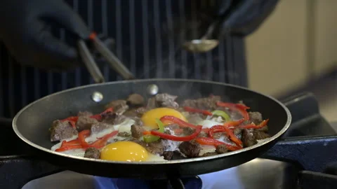 Chef in professional kitchen cooks scrambled eggs in pan Stock Footage 262048200