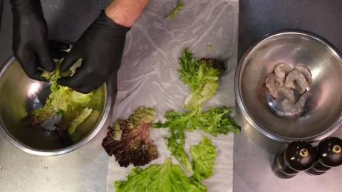 Chef in professional restaurant kitchen tearing lettuce leaves by hand in gloves Stock Footage 334126560