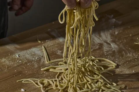 Chef pulling handmade ramen noodles on wooden table Stock-Fotos