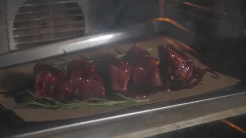 The chef puts a baking tray with pickled pork ribs in the oven in the restaurant Stock Footage 345132345