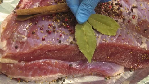 The chef puts a bay leaf on a fresh piece of pork Stock Footage 157981056