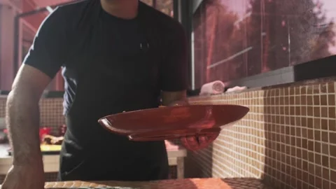 The chef puts carrots with a slotted spoon in a plate with rice from a large Stock Footage 310384673