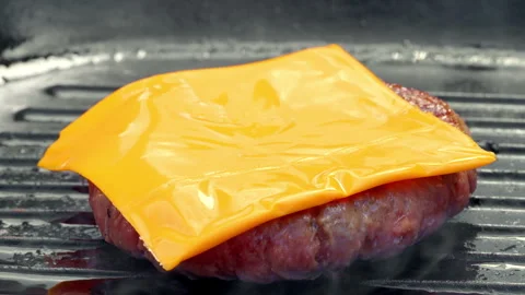 The chef puts cheese on a fresh ground beef burger patty frying in a pan. Stock Footage 315902924