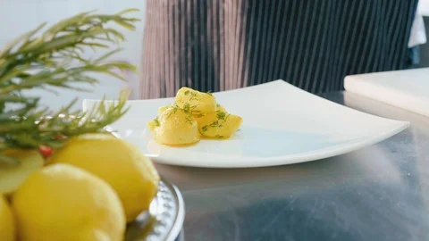 Chef puts a dish of prepared potatoes with herbs in white plate. Stock Footage 91735160