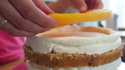 Chef puts the filling from oranges on white sweet cream part. Close up 库存影片 128542680