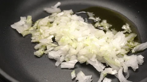 Chef puts finely chopped onion in a hot pan with hot sunflower oil and stiring Stock Footage 164535420