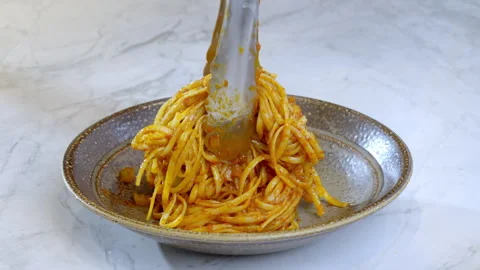 Chef puts finished spaghetti pasta in red sauce from pan onto a plate. Stock Footage 273983436
