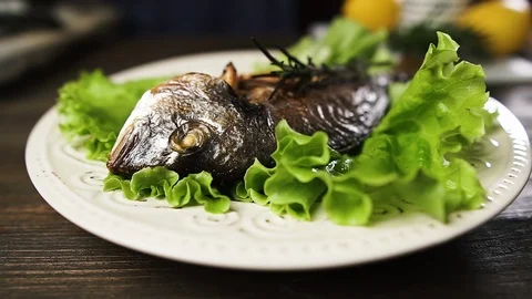 Chef puts fresh baked fish on a plate with green lettuce. Video stock 125581136