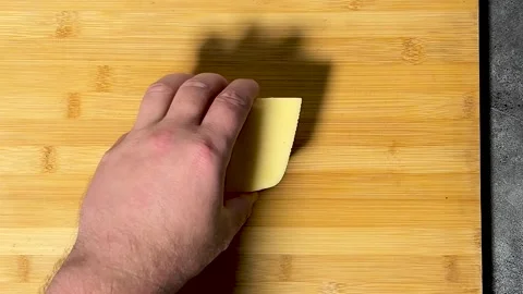 Chef puts fresh yellow cow cheese on wooden cutting board Video stock 295694543