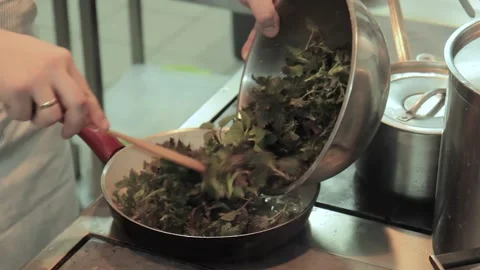 The chef puts the leaves of the nettle into the pan in restaurant kitchen. Chef Stock Footage 131335816