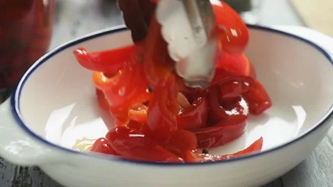 The chef puts the marinated red peppers on the plate with cooking tongs. Stock Footage 207018079