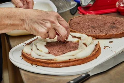 Chef puts the pears inside the pie to make pear and walnut pie Stock Photos