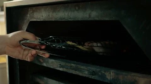 The chef puts a piece of salmon fish, baked vegetables and ribs in the oven in a Stock Footage 92940947