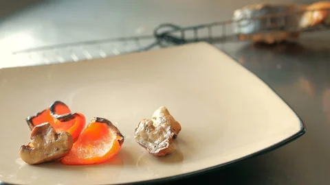 The chef puts a piece of salmon fish, baked vegetables and ribs on a plate in a Stock Footage 92941037