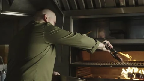 A chef puts a piece of steak on the grill in a restaurant kitchen. Stock Footage 236538587