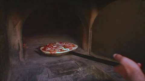 Chef puts pizza into open pizza oven Stock Footage 43216592