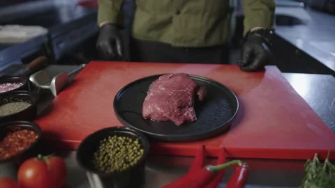 The chef puts a plate of raw meat for the steak. The chef is ready to cook Stock Footage 231430155