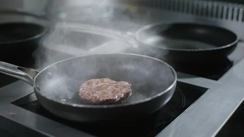 Chef puts raw beef cutlet to the hot pan at the restaurant kitchen Stock Footage 143779206