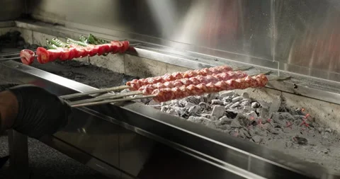 Chef puts raw kebabs on barbecue charcoal grill in a restaurant. Traditional Stock Footage 266725296