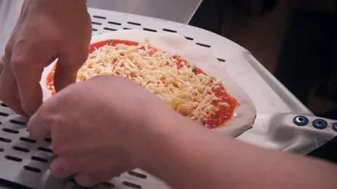Chef puts raw pizza with sauce and spreads dough on spatula Stock Footage 132735119
