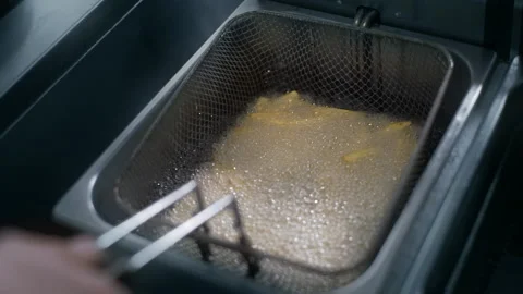 Chef puts raw potatoe to the boiling oil for making fries in slow motion Stock Footage 143779266