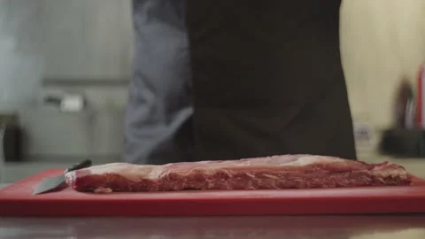 The chef puts raw ribs on the table in the kitchen. Stock-Footage 233812860