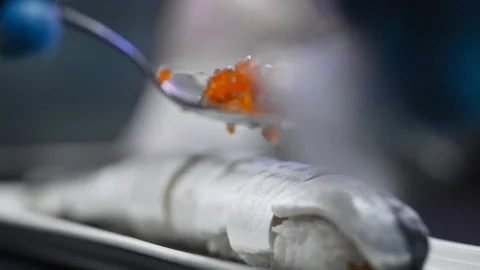 Chef puts red caviar on top of fish pieces on plate at table in kitchen irrl. Stock Footage 128283518