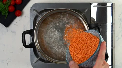 The chef puts red lentils in boiling water. The view from the top. Stock Footage 139511792