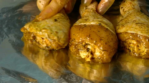 Chef puts in a row raw chicken legs in marinade. Stock Footage 131371438