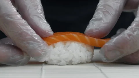 Chef puts salmon slice to the rice making the nigiri in slow motion Stock Footage 143779306