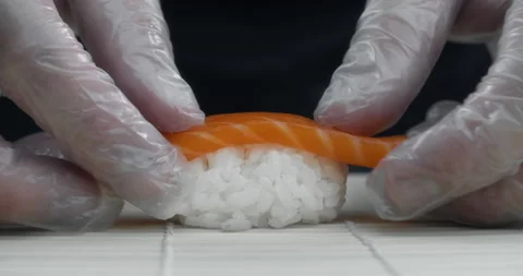 Chef puts salmon slice to the rice making the nigiri in slow motion Stock Footage 143779337