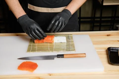 Chef puts salmon while preparing rolls Foto stock