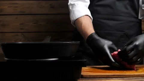The chef puts a shaped ground beef cutlet for a hamburger on a grill pan Stock Footage 197532394