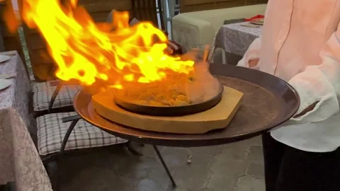 The chef puts on a show with frying pan for guests with burning meat Stock Footage 250963713