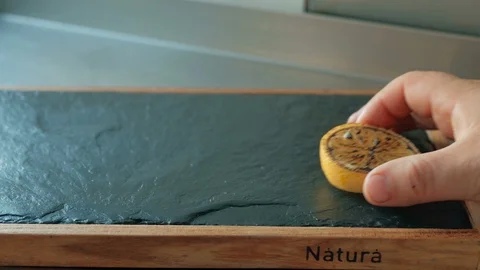 Chef puts a slice of lemon and red pepper on the board for the fish at the Stock Footage 92940407