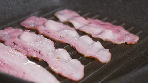 Chef puts slices of fresh raw bacon on the frying pan surface with oil. 스톡 동영상 334642348