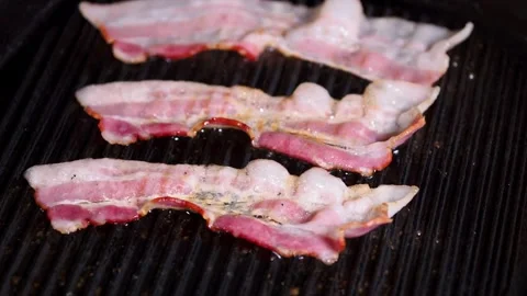 Chef puts slices of fresh raw bacon on the frying pan surface with oil. 스톡 동영상 334642371